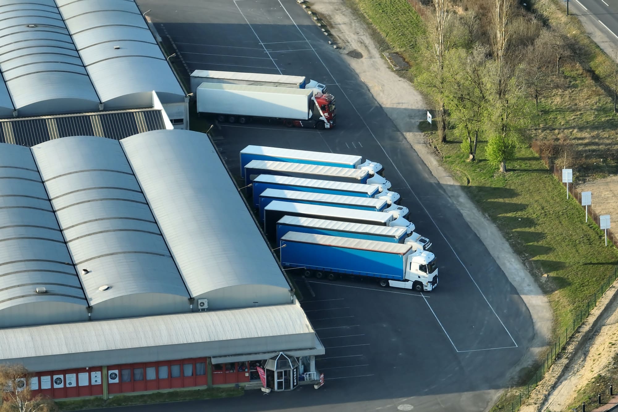 Large commercial trucks and trailers parked behind a warehouse and logistics center