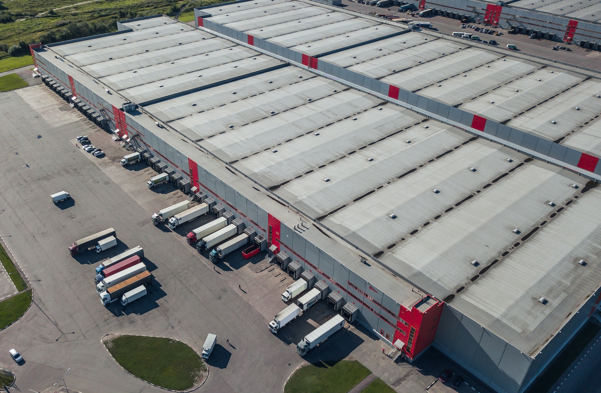 A large logistics center with several trucks and trailers parked in the back for loading and unloading.