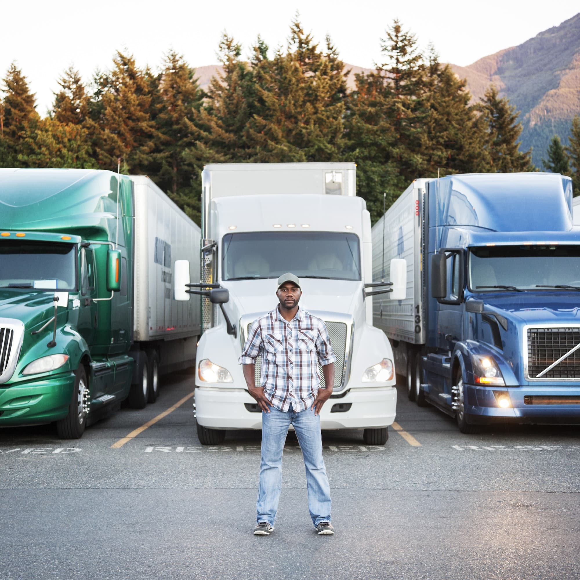 Truck driver near his truck parked in a parking lot at a truck stop