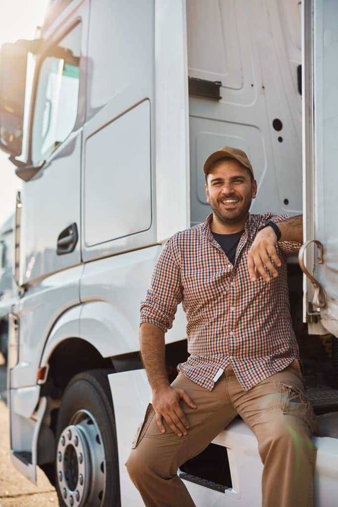 Happy professional truck driver outdoors looking at camera.