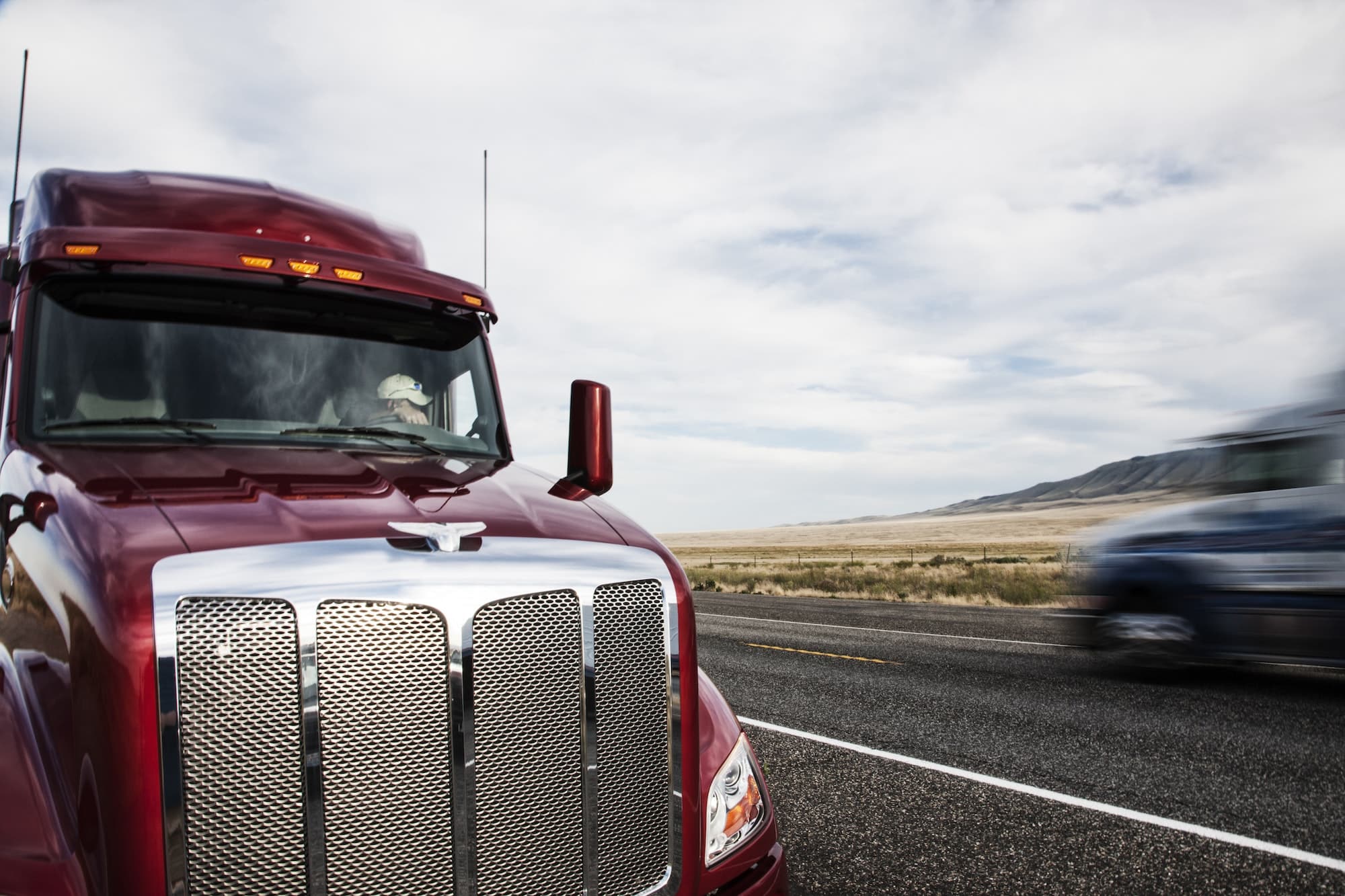 Partial view of the cab on a commercial truck and the highway.