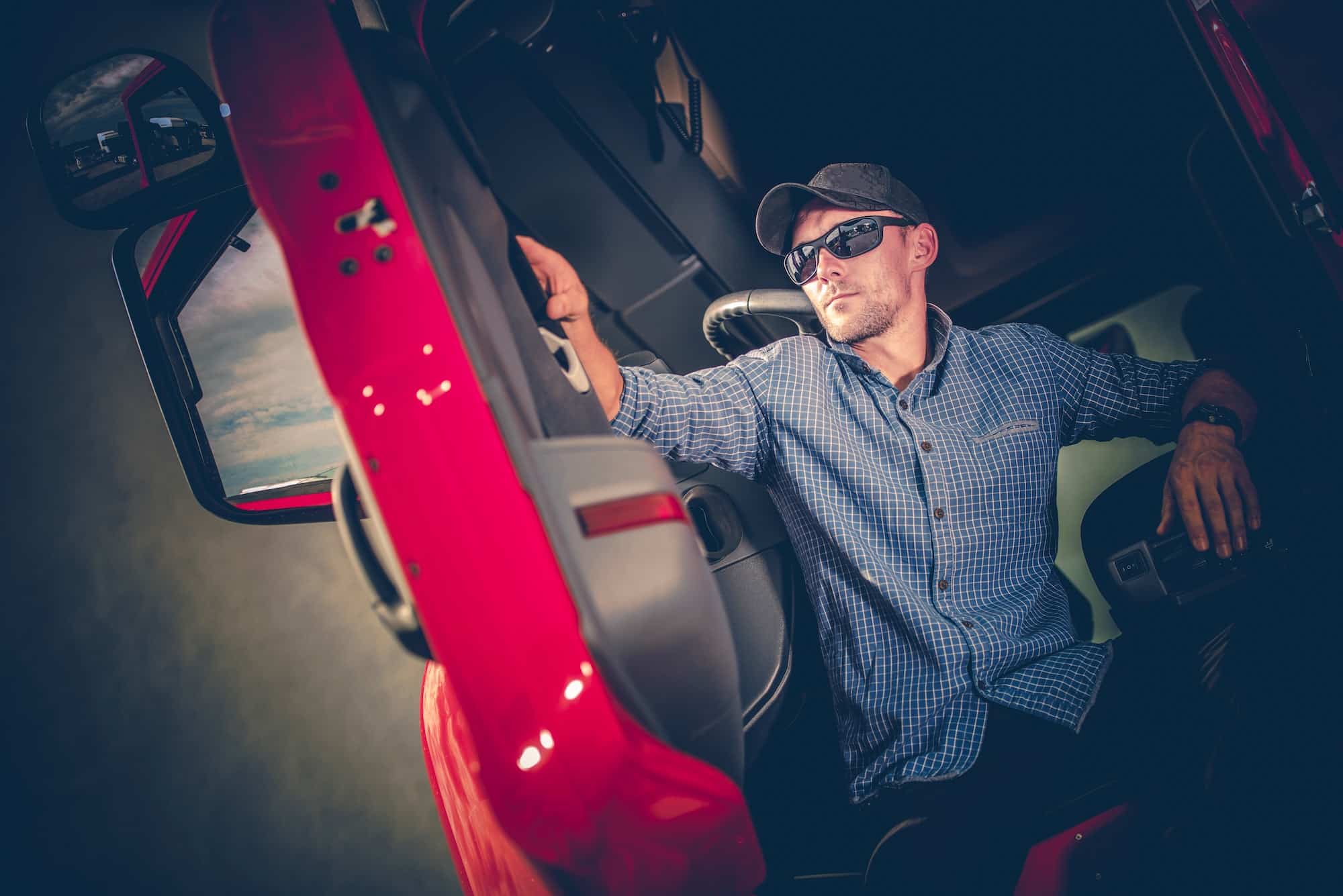 Young truck driver sitting in the cab of his vehicle